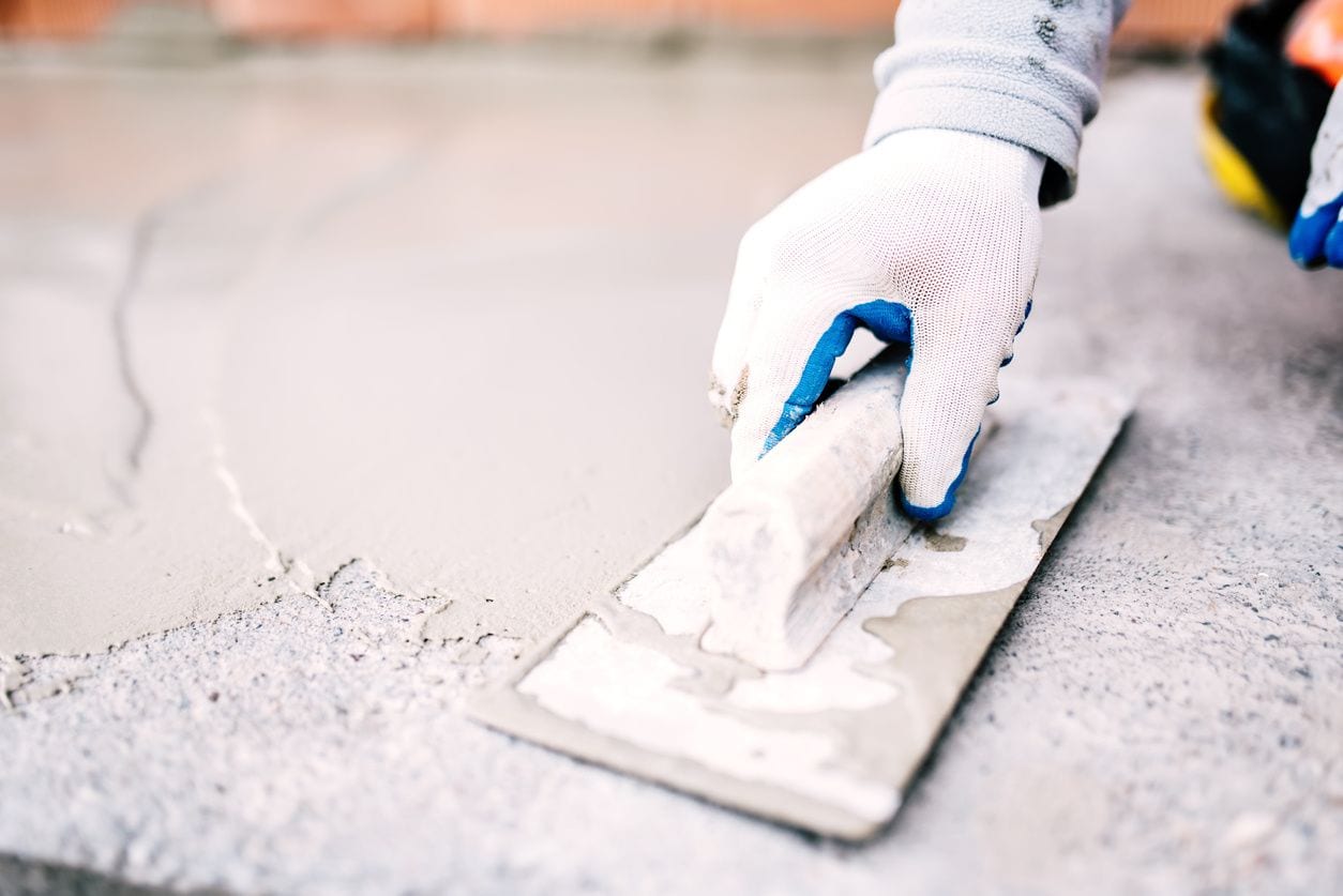 A person with gloves on is using scissors to cut the cement.